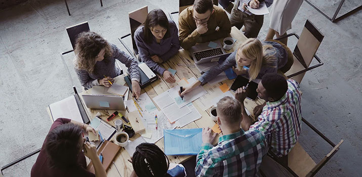 Colleagues in business casual work on strategy documents on a conference table.