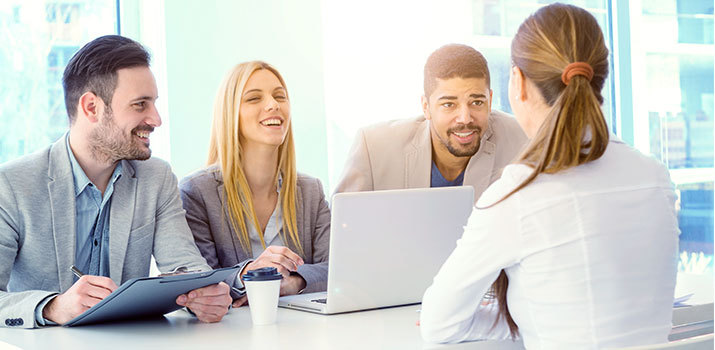 Panel in business attire interviews female candidate.