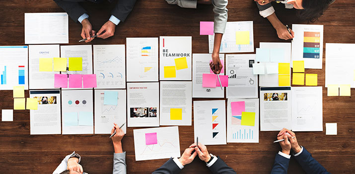 Top-down view of business people arranging marketing plans on a table.