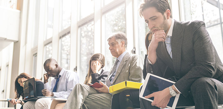 Diverse group of individuals in business attire, seated while waiting for job interviews.